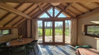 Woonkamer met grote glaswand en uitzicht op het voedselbos